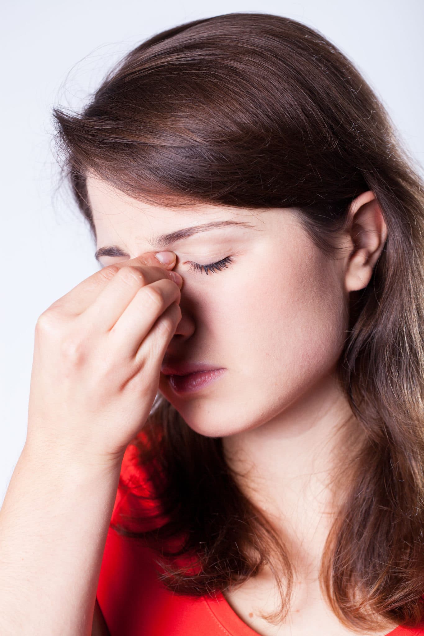 Woman pinching the bridge of her nose to stop a nosebleed.